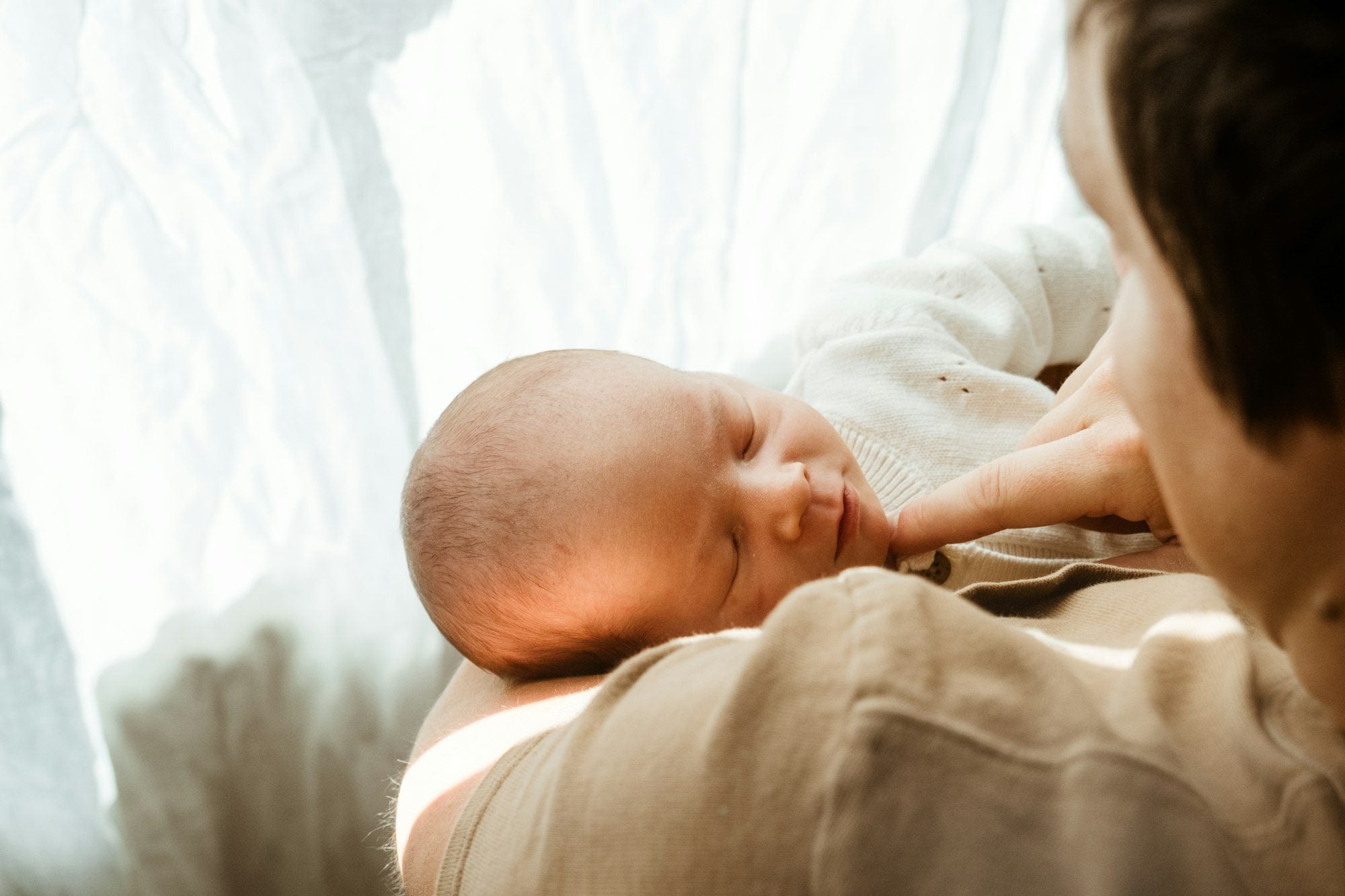 A parent holding their baby close at home in soft morning light
