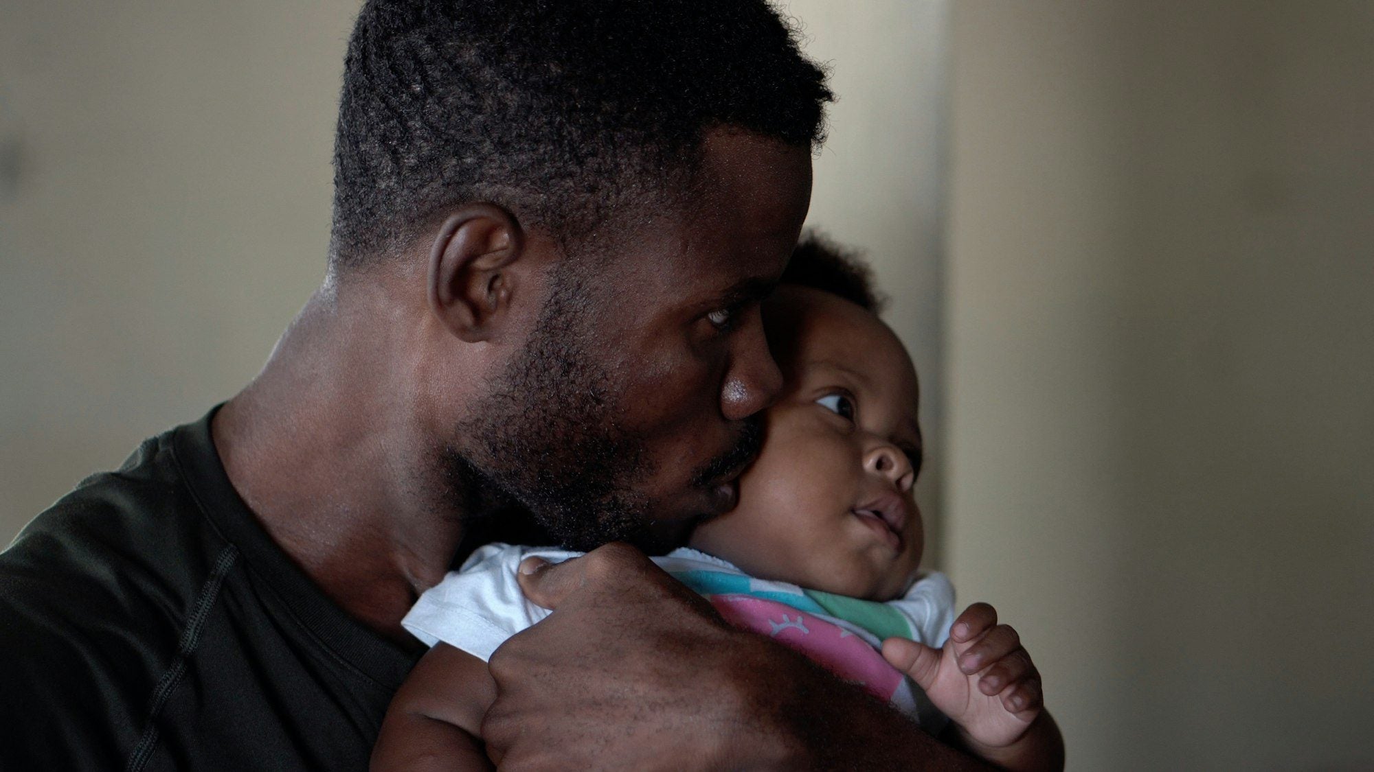 A dad at home kissing his baby