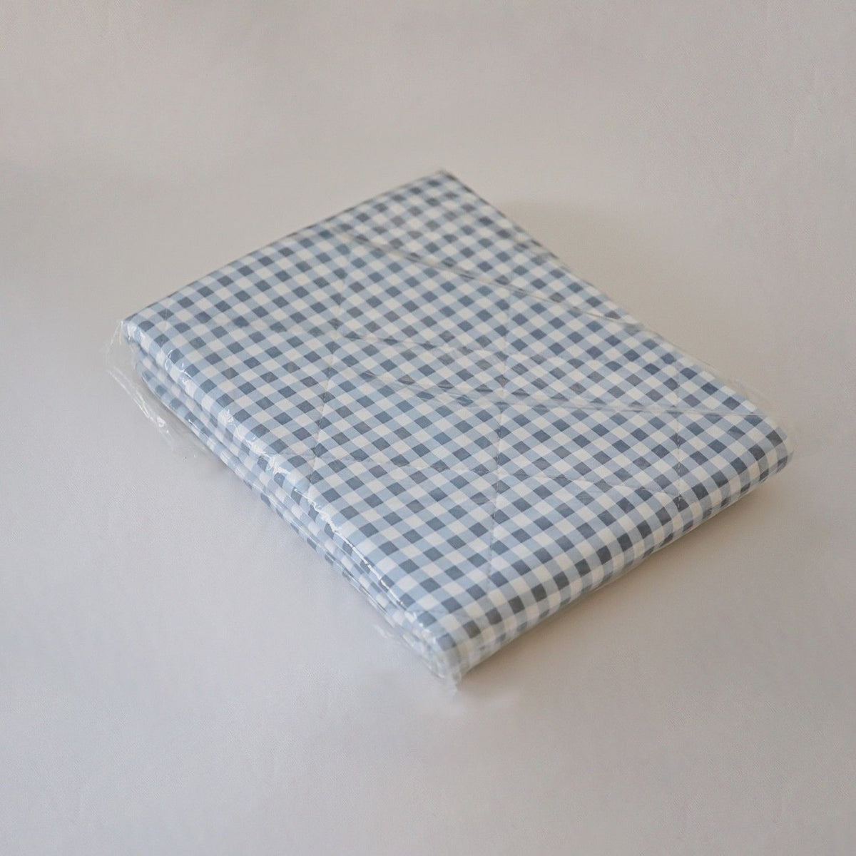 Waterproof Bed Pad: Blue check waterproof bed pad folded flat, showing its quilted thickness