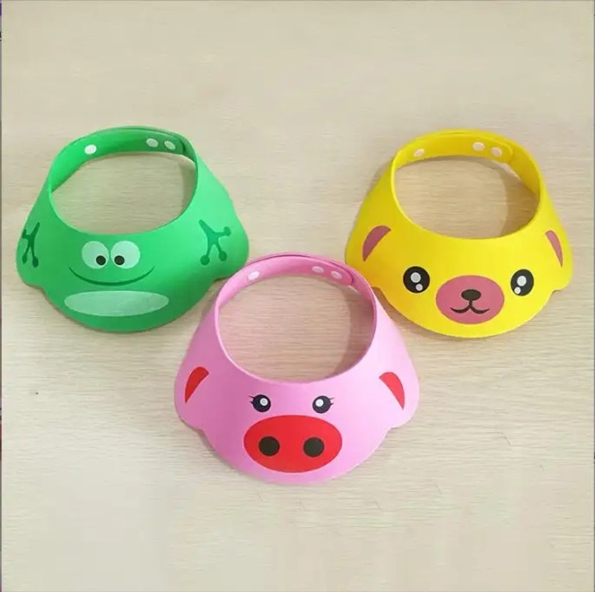 Hair-Wash Shampoo Visor (2-pack): Three foam shampoo visors with frog, pig and bear faces on a table